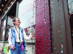 Marg Steele, who volunteers at McNikks on Dundas St. E in downtown Napanee, examines some of the strings of lights that are installed on the storefront. Buildings up and down Dundas, between Centre and John Streets, will light up the downtown on Nov. 22 with the inaugural Big Bright Lights event.     Meghan Balogh, Napanee Guide