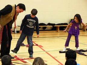 Métis jigger Cobin Poitrais demonstrates to William Anderson, 9, how to do the traditional Métis sash dance during a presentation Thursday at Dr. K. A. Clark School. AMANDA RICHARDSON/TODAY STAFF