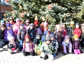 The group of decorating elves pose around the Christmas tree they decorated.