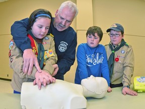 Jay Forslund shows scouts Erin O'Donoughue, Dylan Dorey and Liam O'Donoughue how to perform CPR at Saturday's free public event.