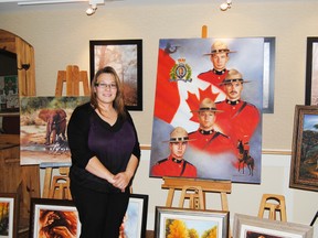 Deanne Jackson poses with an original painting of the Fallen Four during an art show on Nov. 8 at Pleasant Valley Lodge in Mayerthorpe. Jackson painted the picture as a memorial to the four RCMP members that lost their lives in the line of duty in 2005. A copy of the painting is in the Fallen Four Memorial Park.