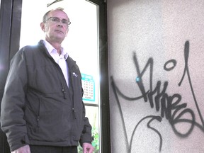 Midwest on Main owner Bob Stevenson stands in front of one of his business’ most recent tags. Stevenson is growing more and more frustrated with vandalism seen in storefronts in the downtown core. (Adam Jackson/Daily Herald-Tribune)