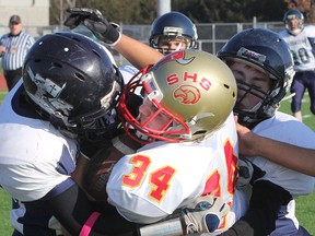Sydenham Golden Eagles’ Brenden Monnier is sandwiched between St. Mary Crusaders tacklers during Monday’s Eastern Ontario Secondary Schools Athletic Association junior double-A football final at CaraCo Field. The Golden Eagles trounced the Brockville team 42-7 to advance to the National Capital Bowl championship game. (Michael Lea/The Whig-Standard)