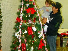 Rikanna Bontrupp helps stepdad Wayne Svederus decorate the tree placed in the Festival of Trees in memory of Rikanna’s late brother Kelsey Bontrupp. Volunteers worked all day Sunday starting at 7:30 a.m. and were  still hard at it 12 hours later. The Festival is open 11a.m. to 9 p.m., Nov. 19-23. On Saturday Nov. 24 is open only 10 a.m. to noon, so if you want to get a bid in on one of the trees or other items you must have it done by noon on Saturday. (Chris Eakin/Fairview Post)