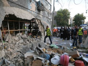 An Israeli municipality worker (C) speaks on his phone as he surveys the damage after a rocket fired from the Gaza Strip landed in the southern city of Ashdod November 20, 2012. REUTERS/Avi Roccah