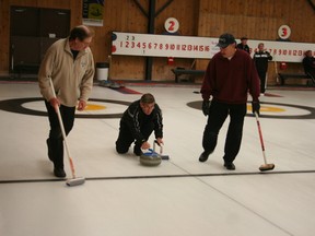 Sweepers Phil Curtis, left, and Claude Charlebois of the Fisher Rink in Iroquois Falls watch as team-mate Dennis Delaurier throws a rock during their game against the Schizkoske Rink from Timmins Tuesday morning. Fisher’s team ended up winning that match.