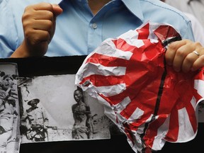 A protester holds a crumpled Japanese Self-Defence Force flag and a banner with pictures of Japanese soldiers and Chinese prisoners of war, during a demonstration in September against Japan's decision to nationalize the islands called Senkaku by Japan and Diaoyu by China. The effect of the rise of such Chinese nationalism on Japanese business in that country does not bode well for other countries – such as Canada – expanding their trade with that country.