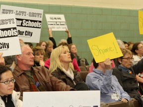 Members of the public hold up signs opposing the closure of secondary schools in the central Kingston catchment area of the Limestone District School Board at a committee meeting Thursday. Senior staff made several recommendations, none of which included keeping all secondary schools in the central area open.