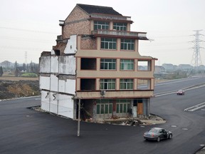 A car stops beside a house in the middle of a newly built road in Wenling, Zhejiang province, November 22, 2012. REUTERS/ CHINA DAILY