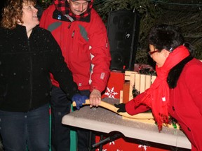 Mayor Dave Canfield gets a helping hand from event organizer Lisa Lyle of Kenora BIZ and Coun. Charito Drinkwalter in throwing the switch to illuminate the Main Street Christmas Tree. The City of Kenora's official Christmas tree lighting ceremony attracted a small but hearty crowd to Main and Second Street S. Thursday evening, Nov. 22.