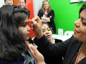 Meera Grover (right), owner of Eye Level, paints a youngster's face at their grand opening on Friday in Sudbury. Jordan Allard/The Sudbury Star