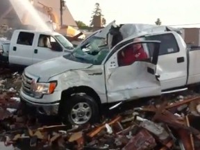 A volunteer firefighter starts up a beaten-up Ford F-150 and drives it over a pile of rubble left behind after Kelleher Ford was gutted by fire in September 2011.