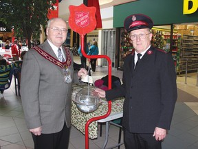 STEPHEN UHLER   On Saturday, Nov. 24, 2012, the Salvation Army 2012 Christmas Kettle Campaign officially kicked off at the Pembroke Mall. Here, Pembroke Mayor Ed Jacyno, left, makes a donation with Major Glenn Wirachowsky of the Salvation Army standing beside the kettle.