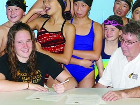 Hannah Sutherland (left) signs her scholarship offer with Division I NCAA school University of Baltimore Maryland County as Coach Gord Emmerson (right) and other young members of the Ernestown Barracudas Swim Club club look on.     Contributed photo