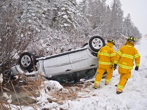 Inter Township firefighters walk past a car upside down in the ditch north of Springmount Monday morning.