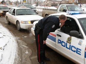 Edmonton Police Service members talk after arresting a suspect in a bank robbery in a Co-Op cab outside Capilano Mall on Monday.