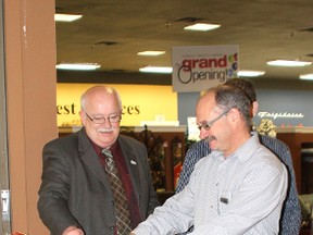 Mayor Bruce Marriott assists store manager Kevin Ford in cutting the ribbon at the official opening of The Brick in the Lakeland Mall Friday morning.