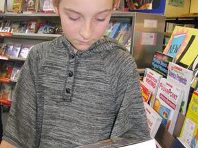 Sydney Davis, 11, an Elmer Elson Elementary School student examines one of the books on display at that school's annual Scholastic Book Fair held in the school's library. She was there for the first day of the Monday, to Friday Nov. 26 to Nov. 30 event. The book that attracted her was Raina Telgemeier's Drama. Sydney said, “I've always wanted to act.”