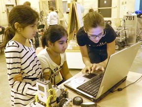 Kinetic Knights veteran and LEGO League mentor Sara Cavasotto (R) demonstrates a concept to Huron Heights students Imaan Afazaal (L) and Priya Kalra while the girls learn to program their robot. (TRACEY HINCHBERGER/KINCARDINE NEWS FREELANCE)