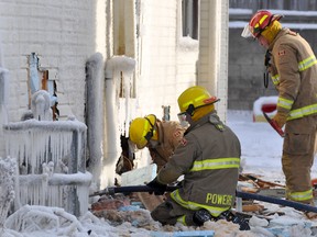 Timmins firefighters, from left, Paul Belair, Aaron Powers and Lieut. Mark Labreche work to get water into the basement of a home at 180 Mountjoy St. S. on Thursday morning. A fire, that broke out at 5 p.m. Wednesday, destroyed the two-storey residence and embers continued to burn in the basement on Thursday.