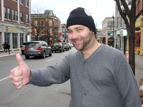 Mark McIntyre, aka, The Gitchhiker, tests out his hitch hiking thumb on Princess Street on Thursday. 
Ian MacAlpine The Whig-Standard