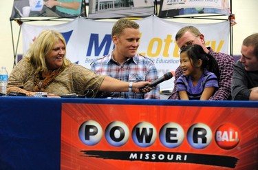 Cindy Hill holds the microphone to six-year old adopted daughter Jaiden, held by husband Mark as sons Jason (2nd L) and Cody (R) look on during a news conference at the North Platte High School in Dearborn, Missouri, November 30, 2012. The Hill family bought one of the two winning tickets for a record $588-million Powerball lottery from the Trex Mart truck stop in Dearborn,Missouri. REUTERS/Dave Kaup