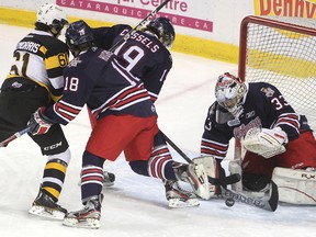 Oshawa Generals goalie Daniel Altshuller reaches for the puck as the Kingston Frontenacs' Mitchell Fitzmorris tries to get past Brian Hughes and Cole Cassels during Friday night's OHL game at the K-Rock Centre. Oshawa went on to win the game 4-2.
Michael Lea The Whig-Standard