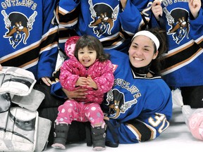 Chatham Moose Lodge Outlaws goalie Courtney Corbiere holds her 20-month-old daughter Brooklyn while posing with teammates after their 3-1 win over the Kent County Fillies in the intermediate division final at the Chatham Girls Hockey Association tournament Sunday at Thames Campus Arena. Corbiere was named the division MVP. (MARK MALONE/The Daily News)