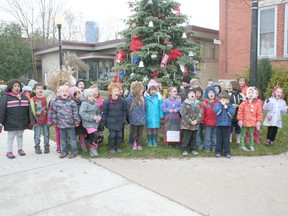 The students stand in front of the newly decorated tree.