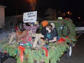 Youths riding on the Rodney Fair Board float Saturday in the Rodney Santa Claus Parade wave and hold up a sign. Residents packed downtown to see dozens of floats and attractions at the evening parade.