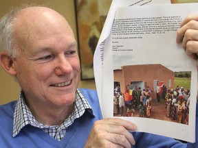 John Telgmann shows a photo of the opening of a medical clinic he helped fund for a small village in the African nation of Mali. (Michael Lea/The Whig-Standard)