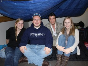 Rachel Reesor, left, Daniel Torres, George Zapata and Lisa Page take shelter in the mock refugee camp at the Education Centre main cafeteria Thursday. A group of students manned the camp until Friday to raise funds and bring awareness to the refugee situation. (PJ Wilson The Nugget)