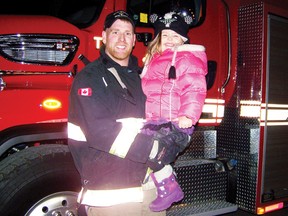 Maddelynn Sage, 3, is held by her father, firefighter Danny Brisebois, during the Ingleside Firefighter’s Association tree lighting ceremony at the Ingleside Fire Department on Saturday.
