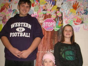 Delhi Public School students, from left,  Bailey Kilmer, Grade 8;  Morgan Condie, junior kindergarten, and Adrianna Booth, Grade 6, stand in front of an anti-bullying pledge tree the student body created for Ontario’s Bullying Awareness and Prevention Week. (SARAH DOKTOR Delhi News-Record)