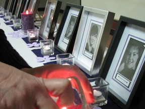 Laura Rominick lights candles prior to the Day of Remembrance event held at the Woodstock CAW Hall. The pictures in behind are of the 14 women murdered at École Polytechnique de Montréal in 1989.