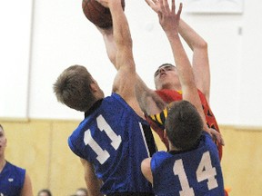 Terry Farrell/daily Herald-Tribune
Sabre shooter Cameron Henrickson is turned away by six-foot-six Titan Ryan Pelster (11) and Will Grosset during league play Wednesday night in Sexsmith.