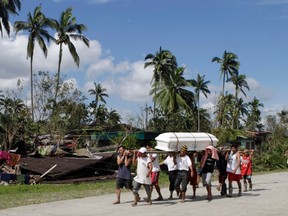 Residents carry the coffin of a typhoon victim past a destroyed house in New Bataan town in Compostela Valley in southern Philippines December 6, 2012. (REUTERS/Erik De Castro)