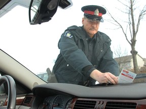 A crime prevention officer with the St. Thomas Police, places a Lock It or Lose It evaluation card on the windshield of this car in St. Thomas in 2011. (QMI Agency file photo)