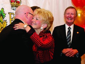 Former Thousand Islands Secondary School principal Arlie Kirkland gets a hug from Leeds-Grenville MPP Steve Clark during a ceremony Friday at the Quality Hotel Royal Brock that saw 67 local citizens receive a Queen's Diamond Jubilee Medal. In background are Leeds-Grenville MP Gord Brown (hidden) and Senator Bob Runciman.