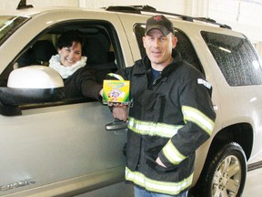 Woodstock firefighter Brad Cullen acepts a donation to Heart FM's annual Toy Truck Campaign from Chris Blum at the Vansittart Avenue fire station on Saturday, Dec. 8, 2012. The doors of the truck bay at the station were open on Saturday so donors could drive through to drop off contributions to the toy drive. JOHN TAPLEY/INGERSOLL TIMES/QMI AGENCY