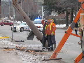 PUC workers examine damage after a car smashed into a telephone pole on Queen Street East Sunday afternoon.
