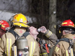 A member of Kingston Fire Department drinks a bottle of water after doing a final walk through of an extinguished house fire.  Fire crews were called to a house fire on 23 Kent Street in Kingston on Saturday, Dec. 8.  No injuries were reported and the cause of the blaze is yet to be known. (Eric Healey/For The Whig-Standard)