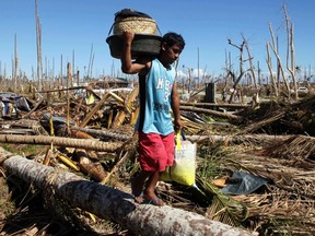 A man carries belongings and relief supplies in a village of the coastal town of Banganga that was devastated at the height of last Tuesday's Typhoon Bopha in Davao Oriental in southern Philippines on December 11, 2012. (REUTERS/Erik De Castro)
