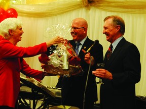 Former Leeds-Grenville federal Liberal candidate Marjory Loveys laughs as she accepts a gift basket from two Tories, Leeds-Grenville MPP Steve Clark, centre, and Senator Bob Runciman at Clark's annual Christmas reception Sunday.
(RONALD ZAJAC/The Recorder and Times)