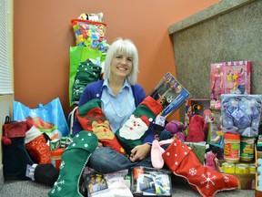 Leslie Cassidy-Amadio looks pleased with the array of Christmas gifts she found at the Prince Township Municipal Office last week.  The items, donated to her JOYfull Socks campaign by Prince residents and firefighters, will go to make Christmas merrier for patrons of Soup Kitchen Community Centre, in Sault Ste. Marie.