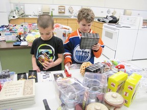 Wacy Inglis, left, 6, and Tyler Erickson, 7, both Grade 2 Sangudo Community School students, check out the merchandise offered for the Jolly Jingle Christmas shopping event in which the proprietor of Your Dollar Store in Barrhead, brings items to the school to allow the children to shop comfortable and in a safe, supervised environment.