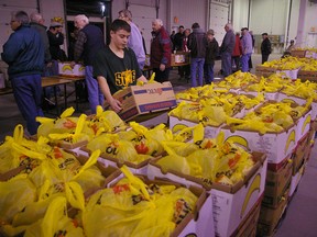 While Golden K Kiwanis and Union-South Yarmouth Optimist service club members behind him pack potatoes on Tuesday at Christmas Care, Arthur Voaden Secondary School Grade 9 student Brian Moyes hefts boxes of the five-pound bags of spuds. ERIC BUNNELL/Times-Journal/QMI Agency