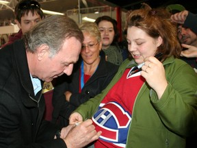 Former Montreal Canadiens great Guy Lafleur signs a Habs jersey for fan Candace Lariviere between periods of a charity hockey game played at the McIntyre Arena Wednesday night. Lafleur was the coach of the Habs alumni team. Photo taken in Timmins on March 7, 2012.