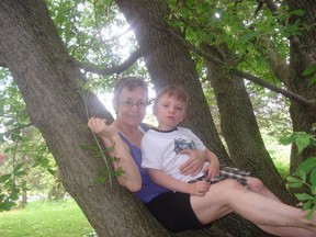 Mary Ellen Csamer sits in a tree with her grandson Joseph, who has autism. Csamer has written a collection of poems, most of them about Joseph.