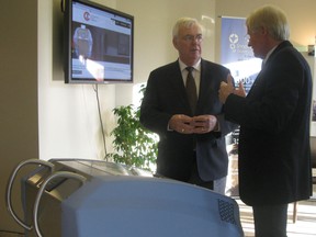 John Gerretsen, left, MPP for Kingston and the Islands, and Dr. Michael Shannon, stand in front of the AsepticSure system, developed by Dr. Shannon and Dr. Dick Zoutman at the Innovation Park facility. (Hilary Thomson/For The Whig-Standard)